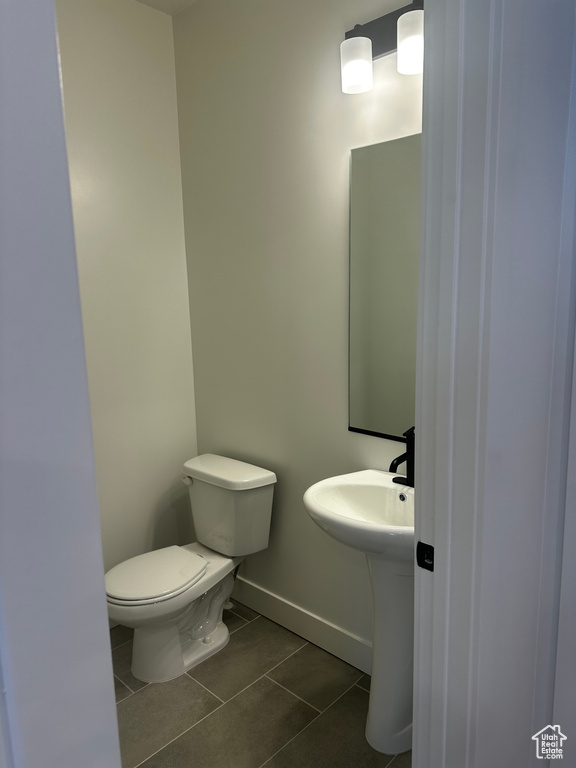Half bathroom featuring tile patterned floors, toilet, and baseboards