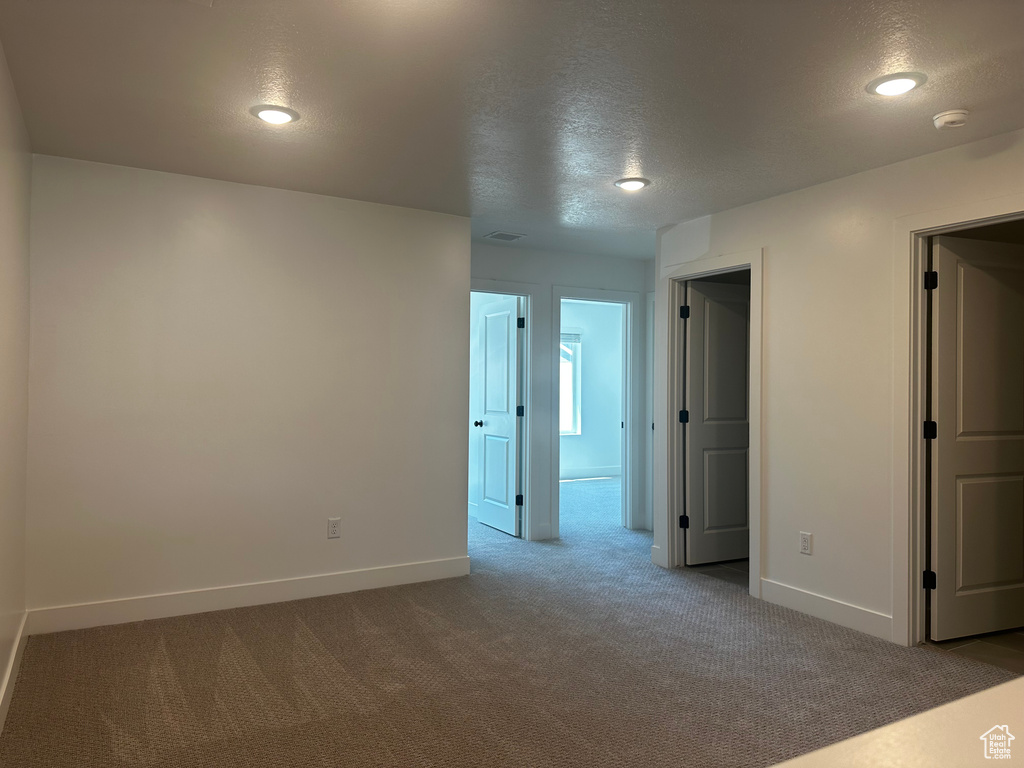 Carpeted spare room with a textured ceiling, baseboards, a smoke detector, and recessed lighting