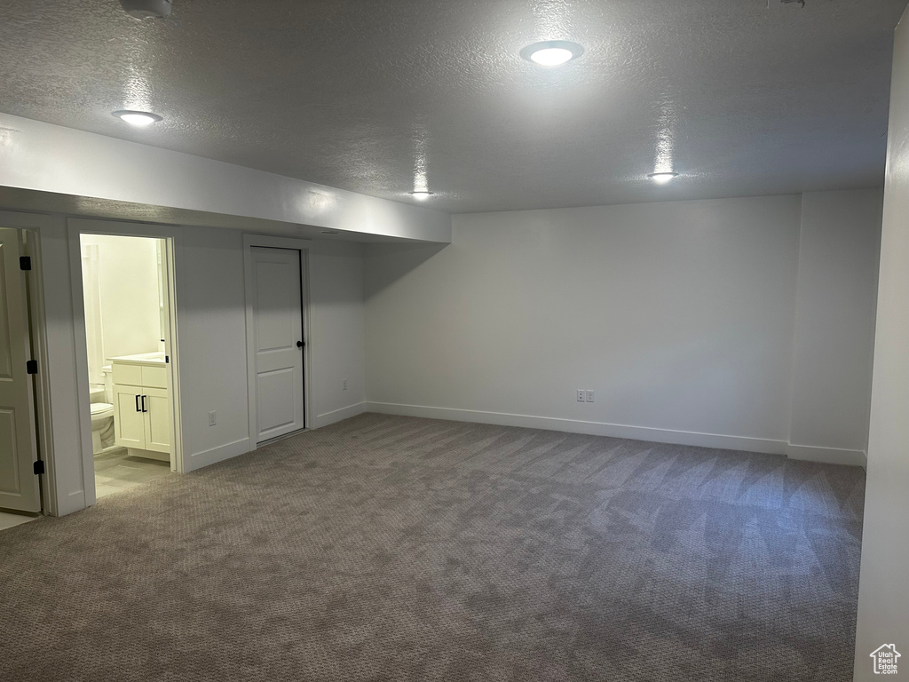 Finished basement with carpet flooring, a textured ceiling, and baseboards