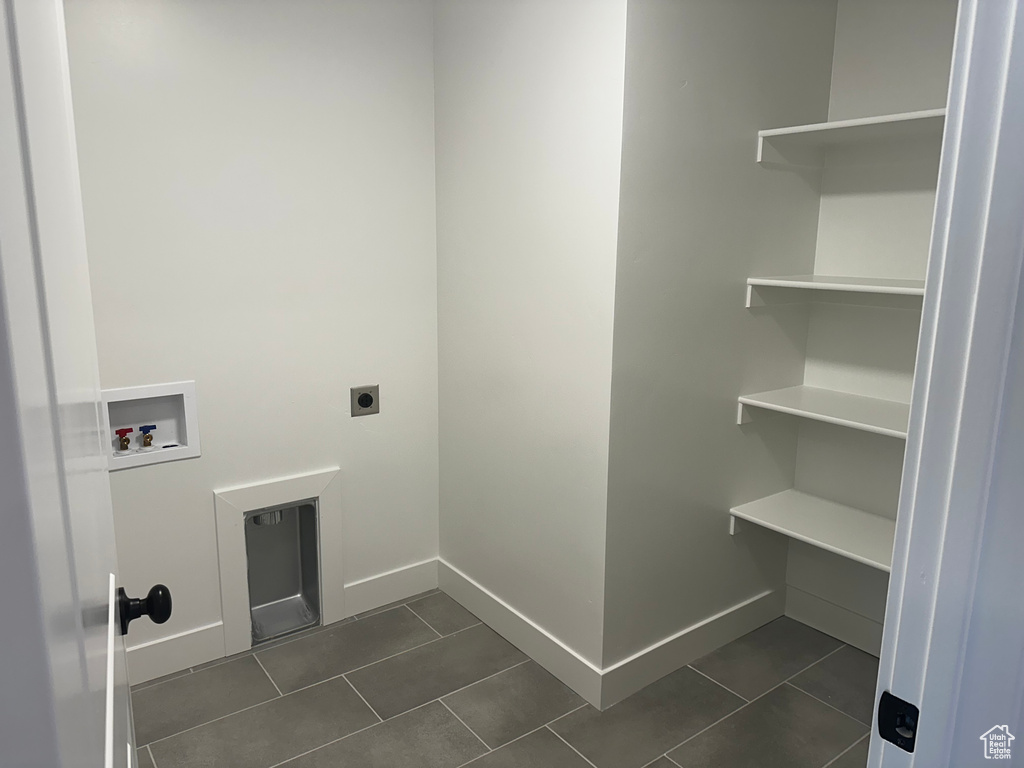 Washroom with hookup for a washing machine, hookup for an electric dryer, dark tile patterned floors, and baseboards