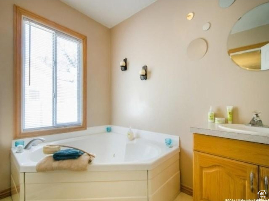 Bathroom featuring plenty of natural light, a garden tub, and vanity