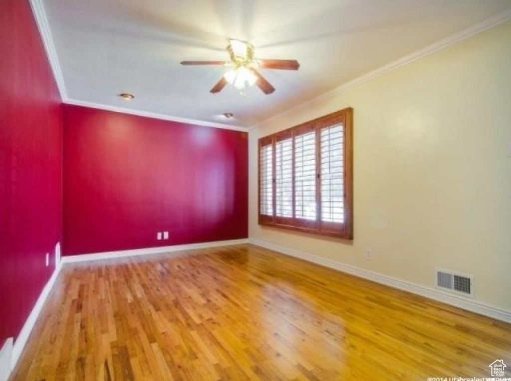 Unfurnished room with a ceiling fan, ornamental molding, wood finished floors, and baseboards