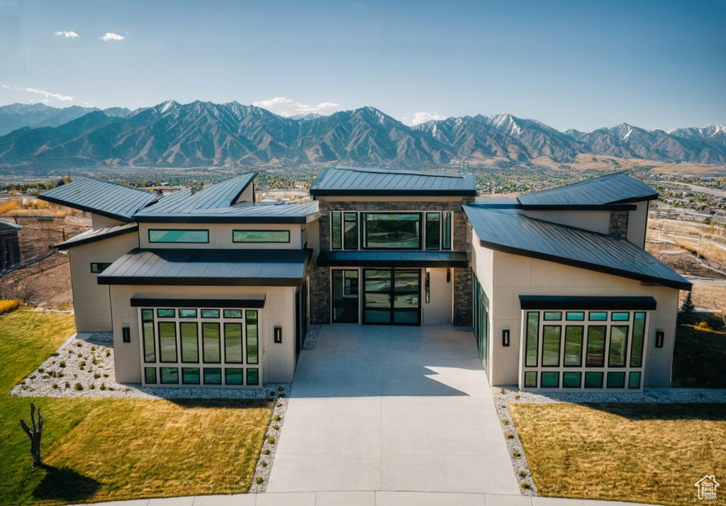 Contemporary house featuring concrete driveway, a mountain view, and stone siding