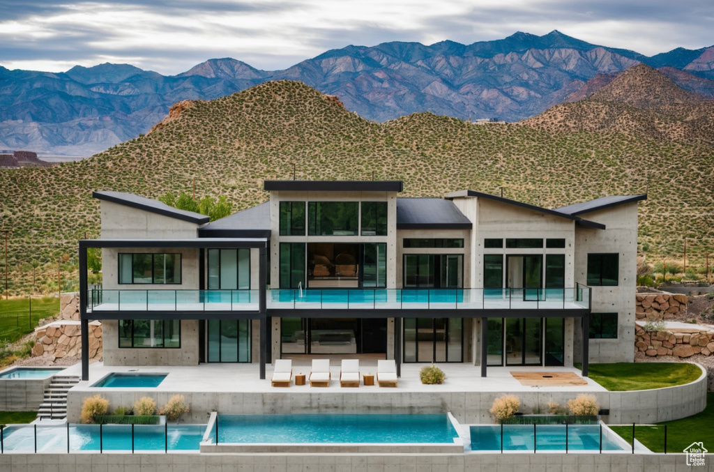Rear view of house with a balcony, a mountain view, outdoor lounge area, a patio, and a pool with connected hot tub