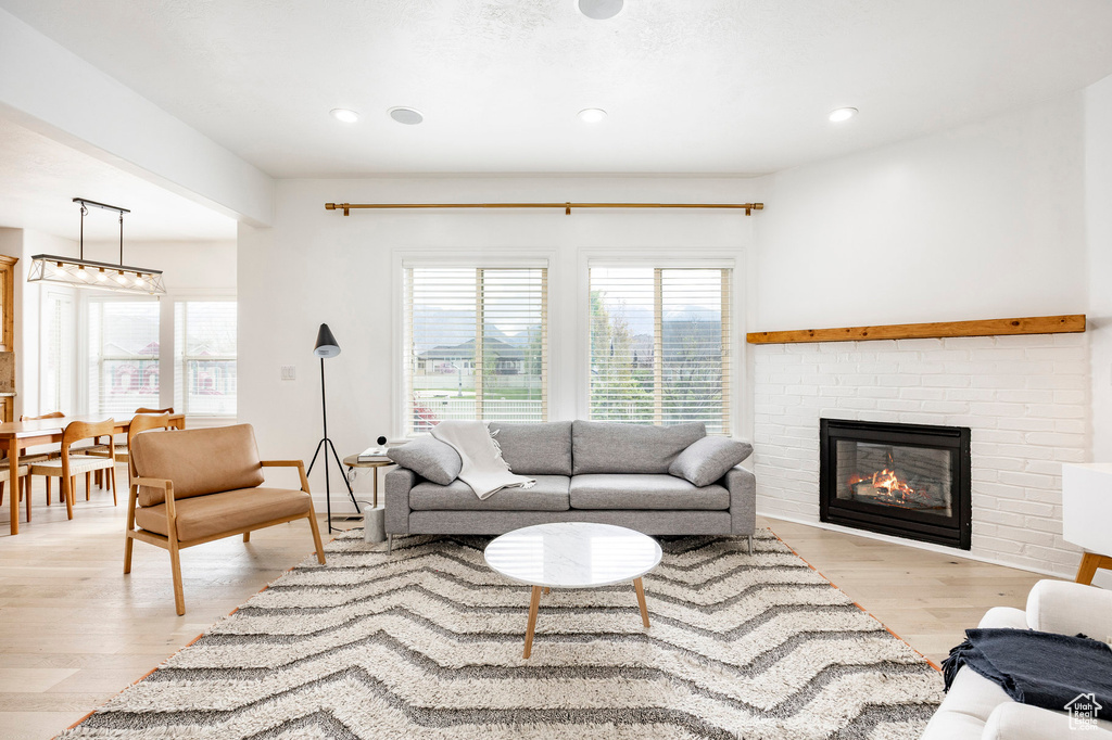 Living room featuring light wood finished floors, a brick fireplace, and recessed lighting