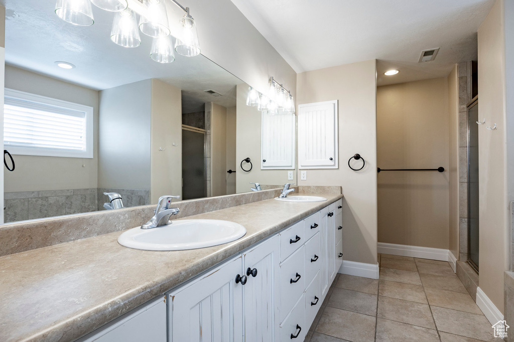 Bathroom with double vanity, tile patterned flooring, a stall shower, and a sink