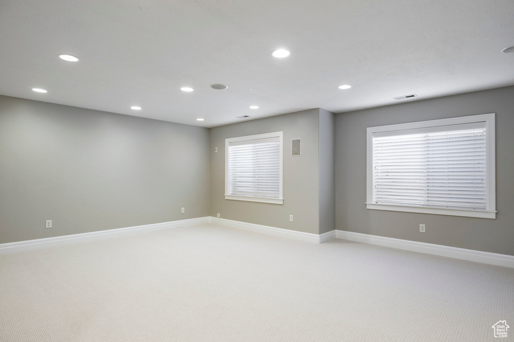 Unfurnished room featuring baseboards, light carpet, recessed lighting, and plenty of natural light