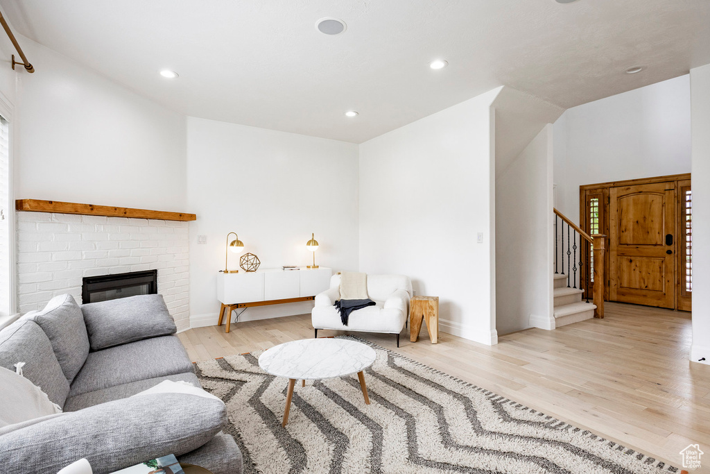 Living area with a fireplace, stairway, baseboards, light wood-style floors, and recessed lighting
