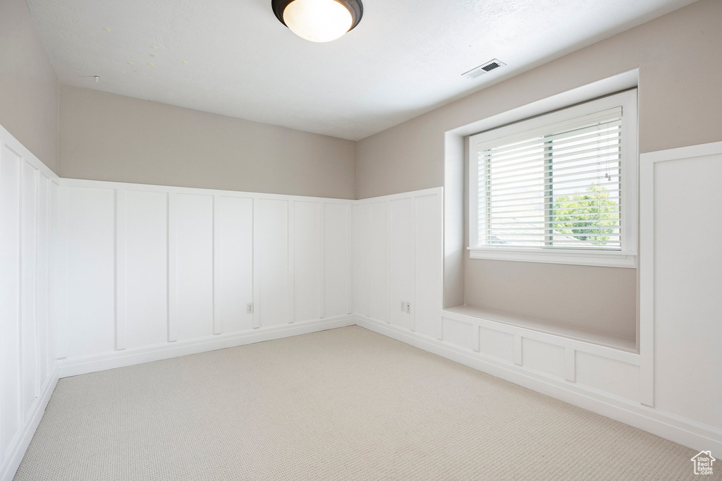 Empty room with light colored carpet and visible vents