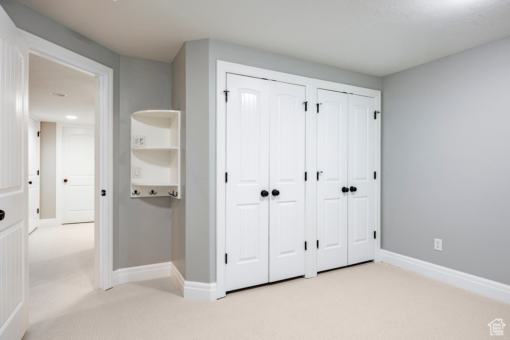 Unfurnished bedroom with baseboards, carpet flooring, and two closets
