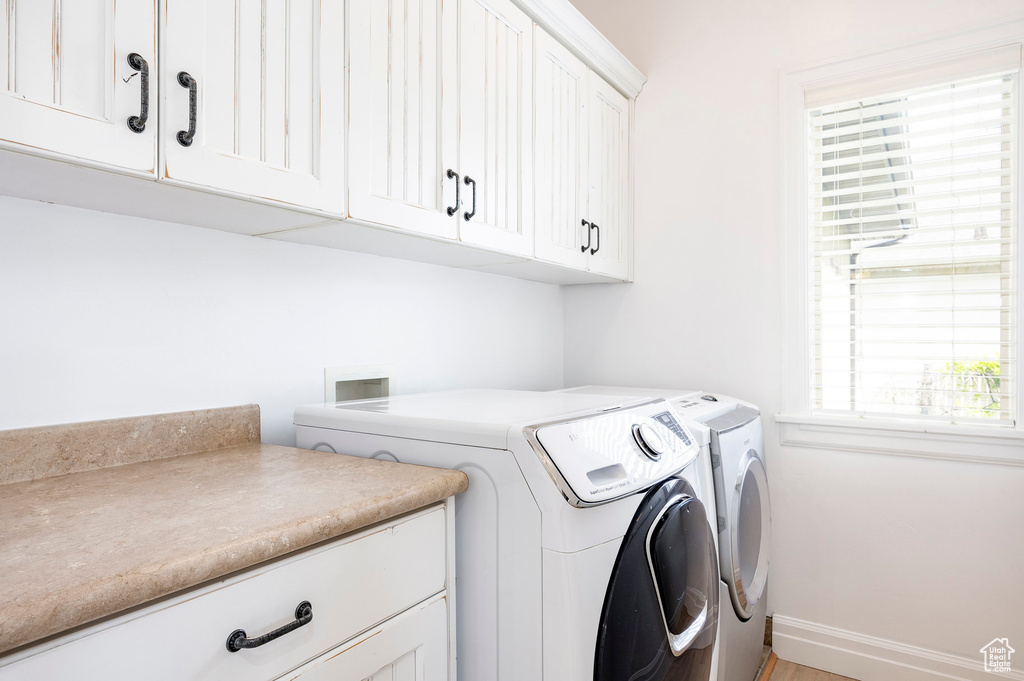 Washroom with baseboards, a wealth of natural light, washing machine and dryer, and cabinet space