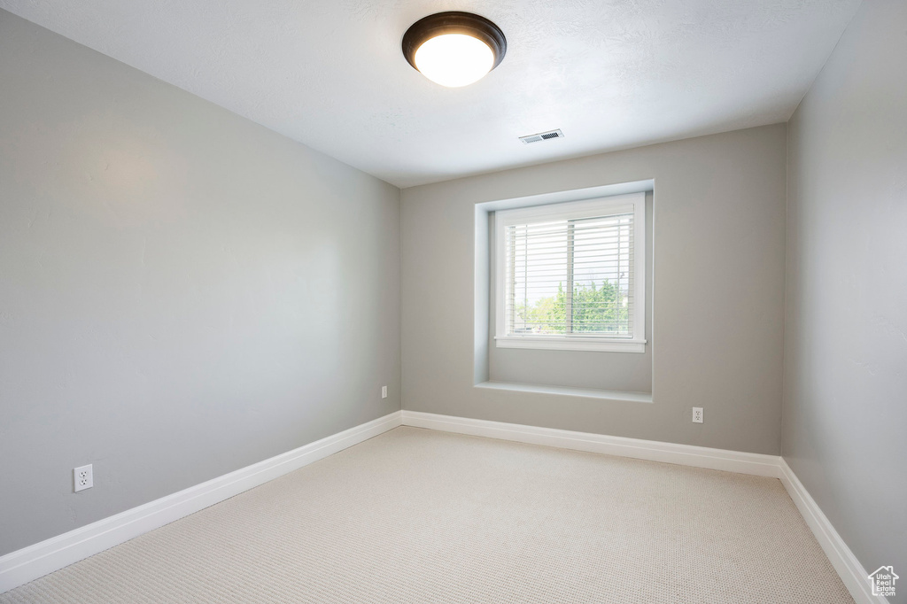 Unfurnished room with light colored carpet, visible vents, and baseboards