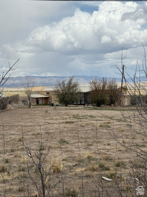 View of yard featuring fence, a view of countryside, and a mountain view