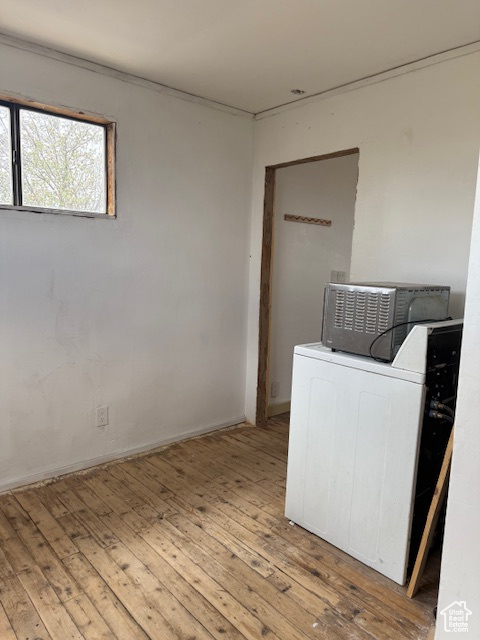 Clothes washing area with washer / dryer, hardwood / wood-style floors, and baseboards