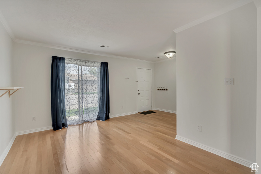 Unfurnished room with light wood-style flooring, baseboards, and ornamental molding
