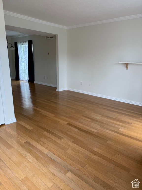 Spare room with light wood-style floors, baseboards, and crown molding