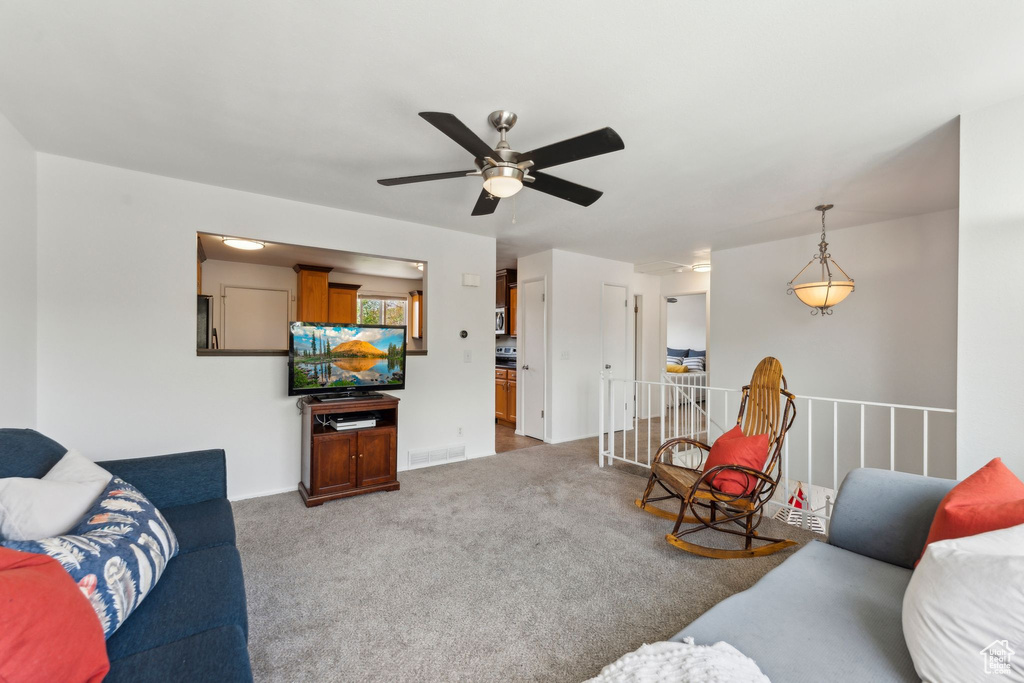 Carpeted living area featuring ceiling fan