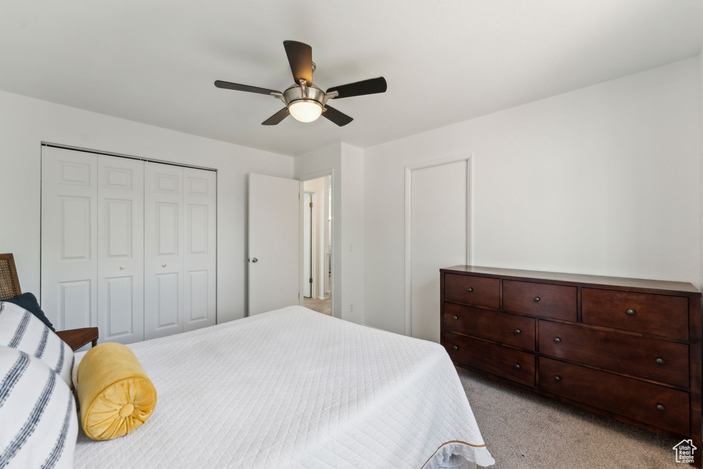 Bedroom with light carpet, a ceiling fan, and a closet