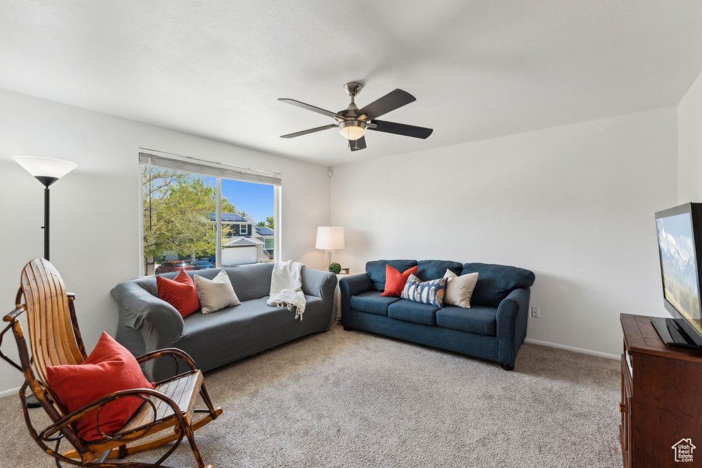 Carpeted living area with ceiling fan and baseboards