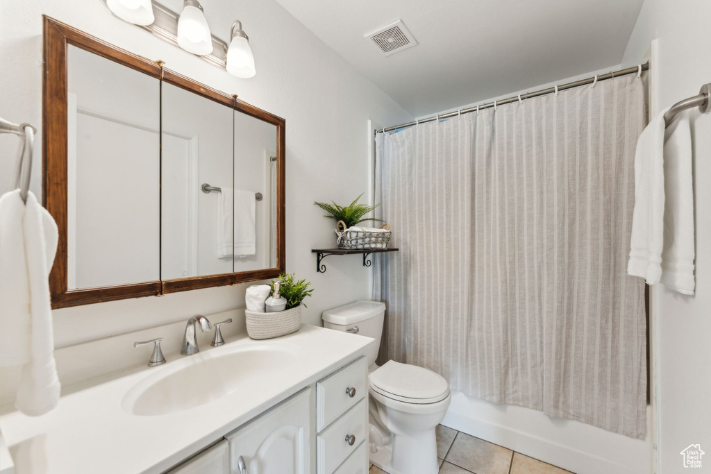 Bathroom featuring toilet, vanity, tile patterned flooring, and shower / bath combination with curtain