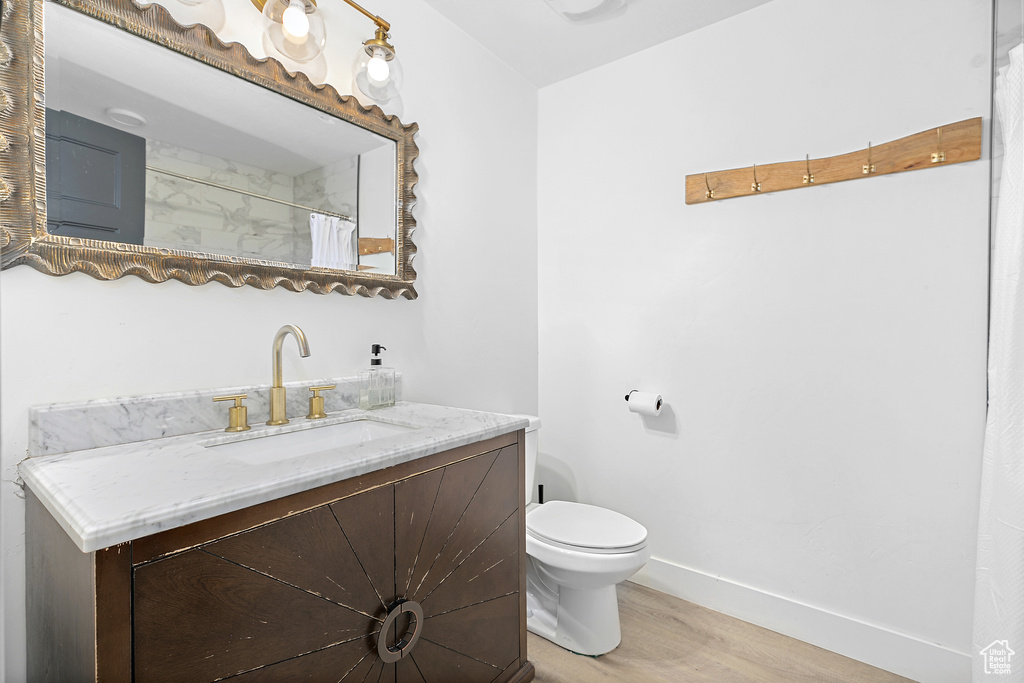 Bathroom with toilet, baseboards, wood finished floors, and vanity