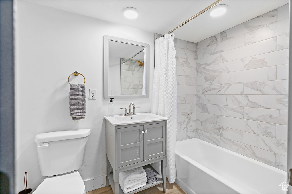 Full bathroom with shower / bath combo with shower curtain, toilet, and vanity