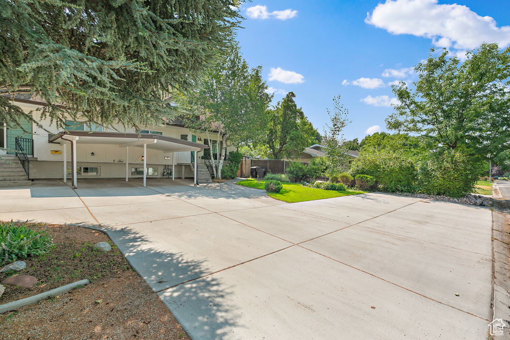View of front of house with an attached carport, driveway, stairway, and fence