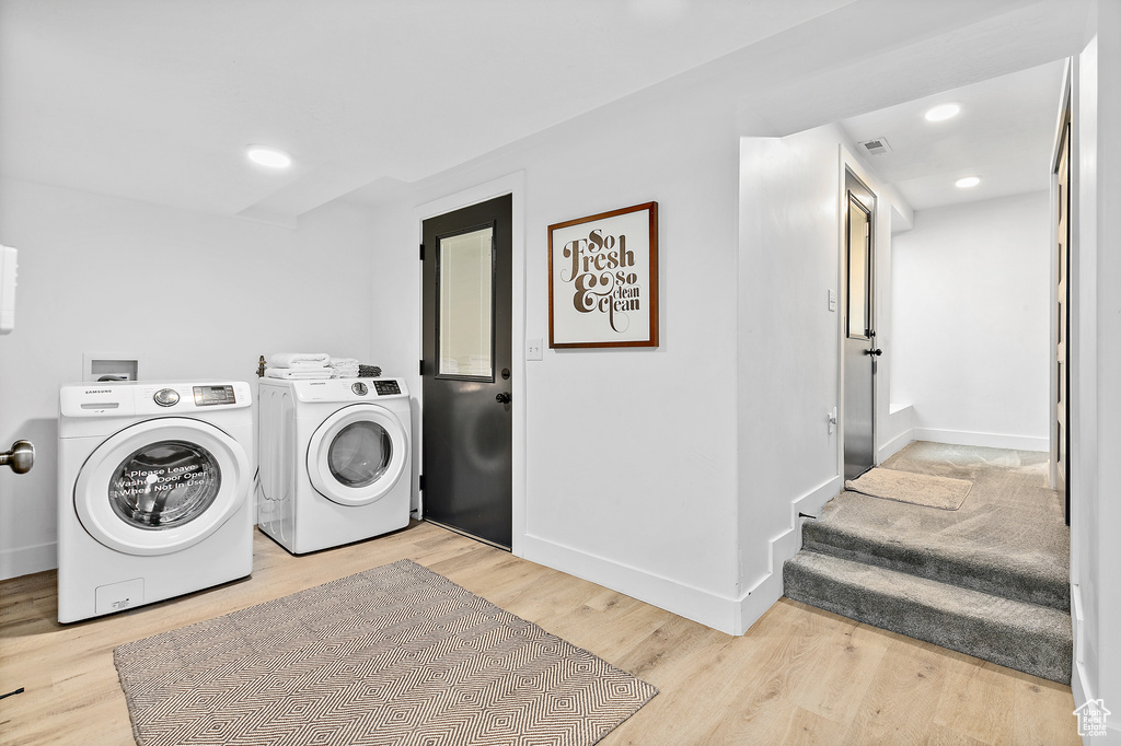 Clothes washing area featuring laundry area, light wood-type flooring, visible vents, baseboards, and independent washer and dryer