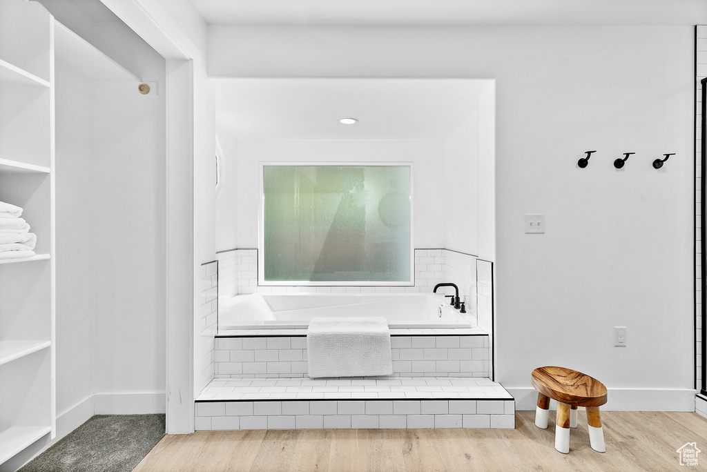 Interior details featuring a bath, wood finished floors, and baseboards