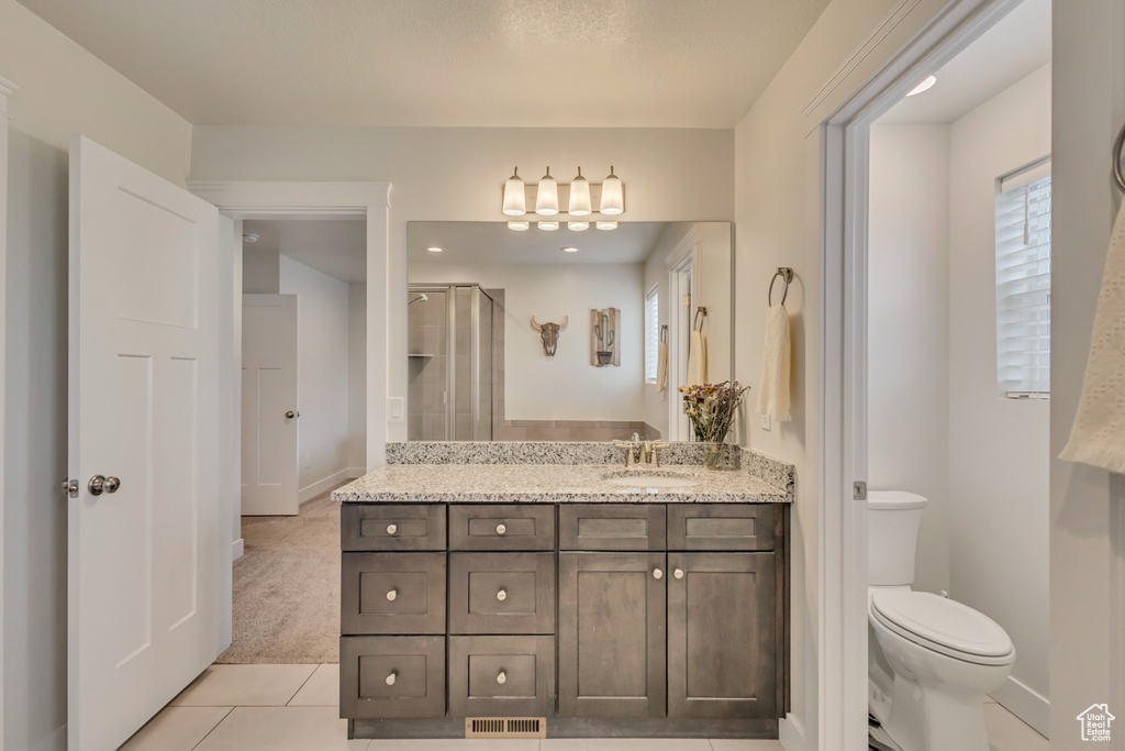 Full bath featuring tile patterned floors, toilet, vanity, a chandelier, and a stall shower