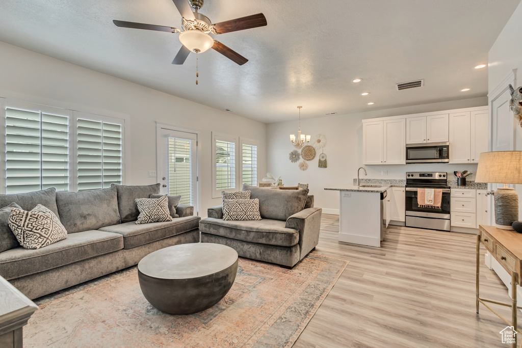 Living room with a chandelier, recessed lighting, light wood-style flooring, a ceiling fan, and baseboards