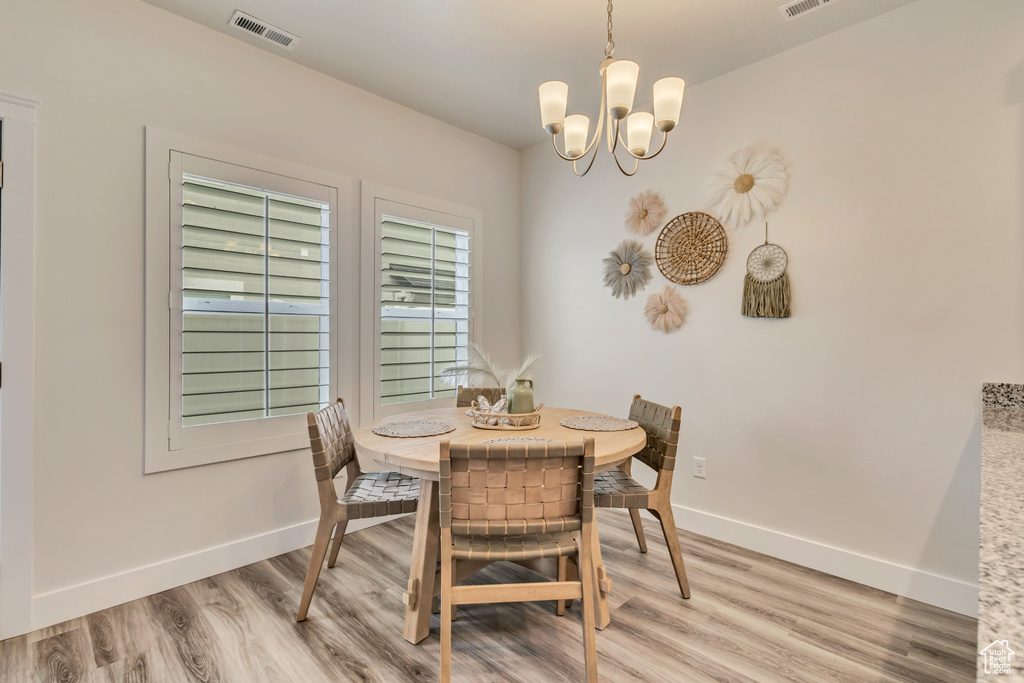 Dining room with baseboards, light wood finished floors, and a chandelier