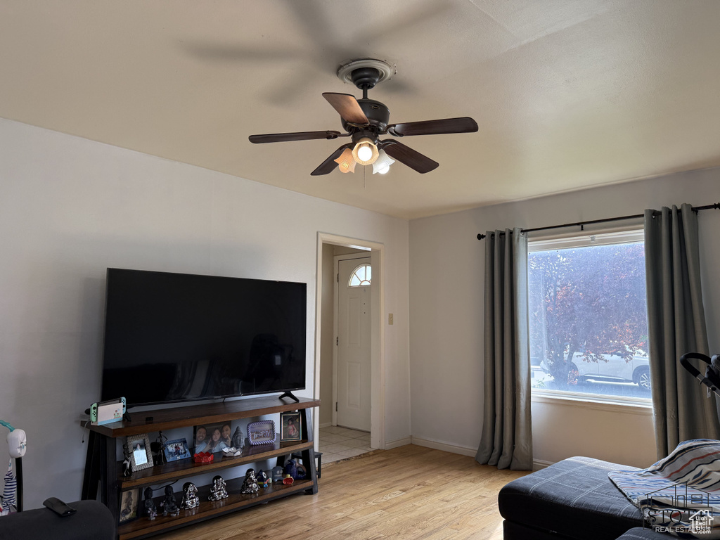 Living room with ceiling fan, light wood-style flooring, and baseboards