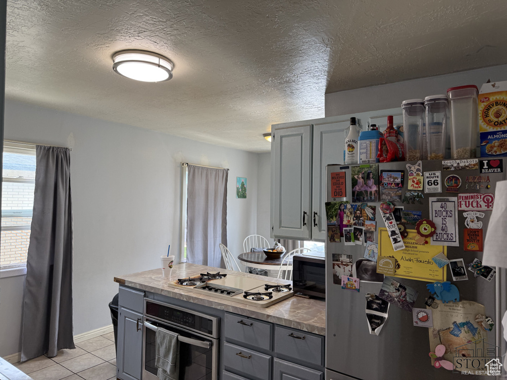 Kitchen featuring appliances with stainless steel finishes, gray cabinetry, light tile patterned floors, light countertops, and a textured ceiling
