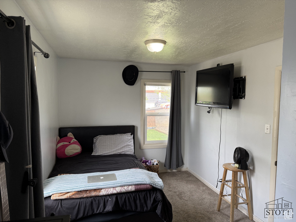 Bedroom with carpet flooring, a textured ceiling, and baseboards