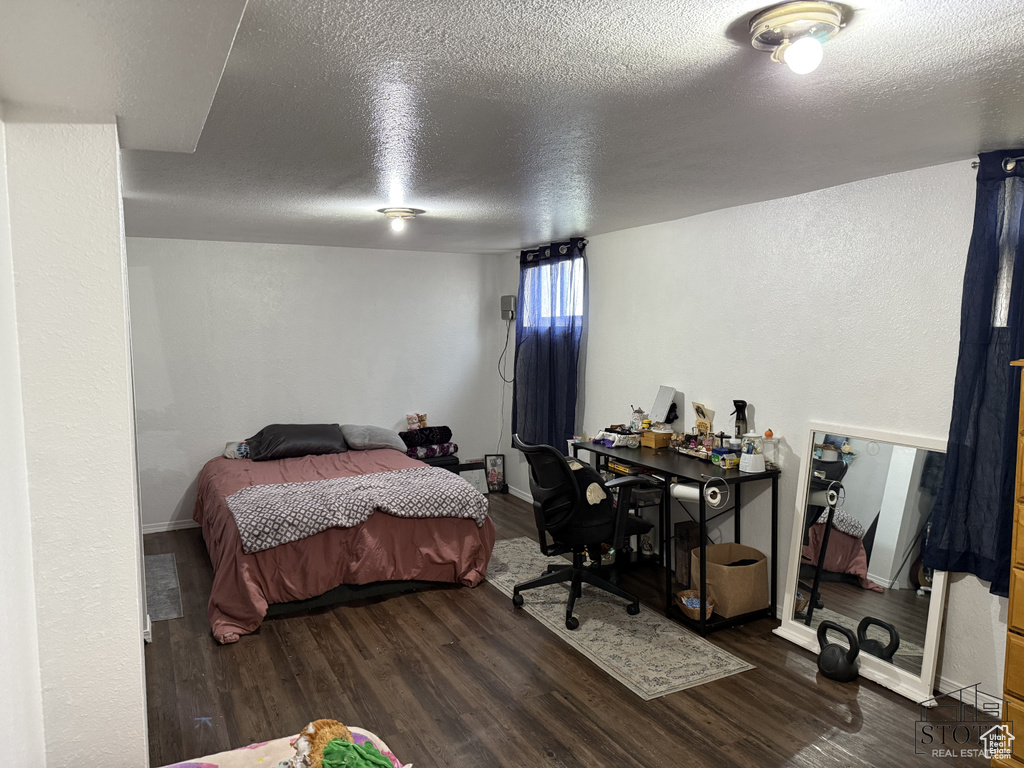 Bedroom with a textured ceiling, wood finished floors, and baseboards