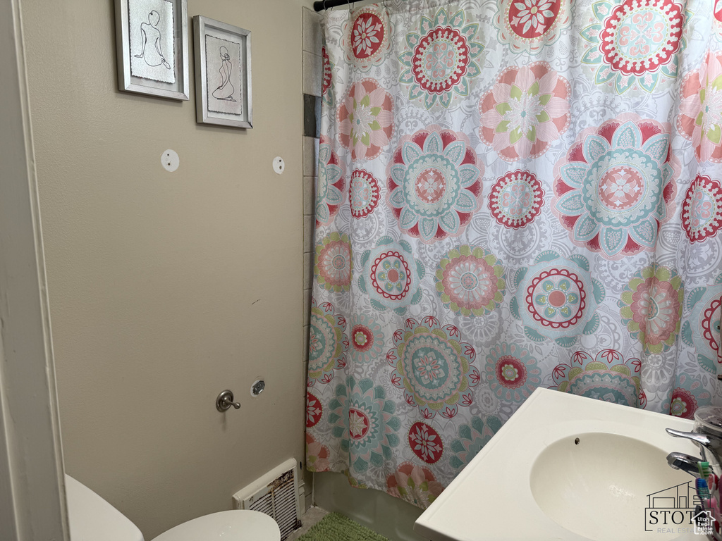 Full bath featuring a sink, toilet, and shower / bathtub combination with curtain