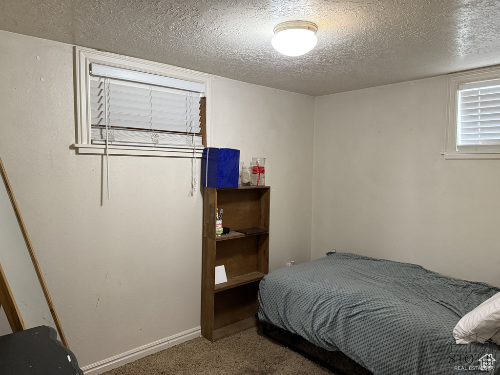 Carpeted bedroom featuring a textured ceiling and baseboards