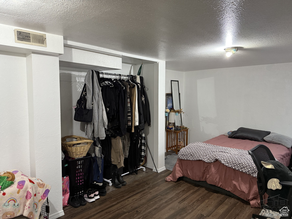 Bedroom featuring dark wood finished floors, a textured ceiling, a closet, and baseboards