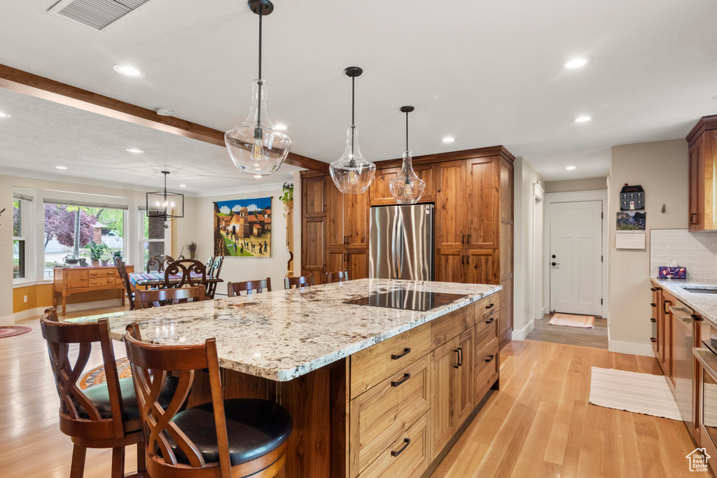 Kitchen with freestanding refrigerator, black electric cooktop, baseboards, light wood finished floors, and recessed lighting