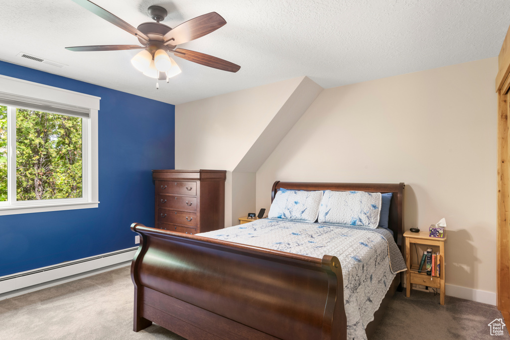 Carpeted bedroom featuring a baseboard radiator, baseboards, ceiling fan, and a textured ceiling