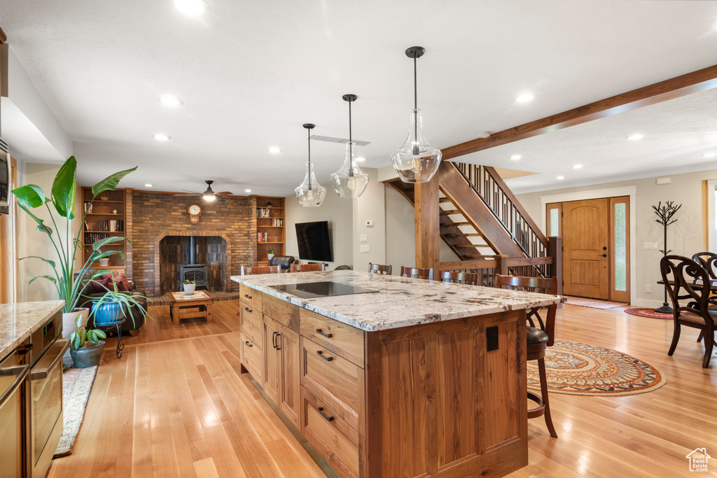 Kitchen featuring open floor plan, recessed lighting, light wood finished floors, a breakfast bar, and ceiling fan