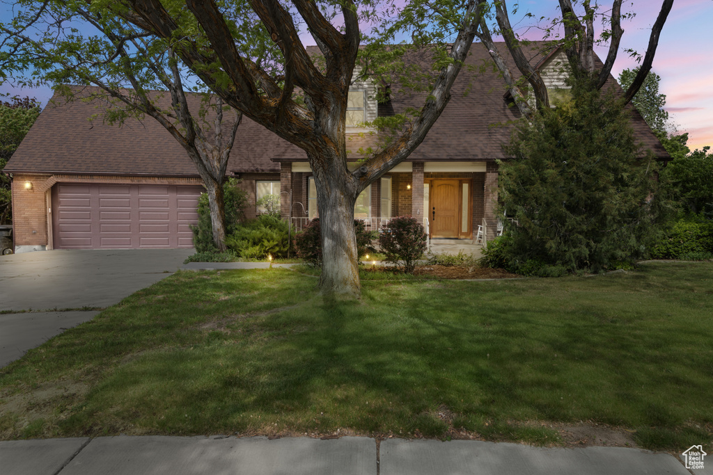 View of front facade with brick siding, concrete driveway, an attached garage, and a lawn