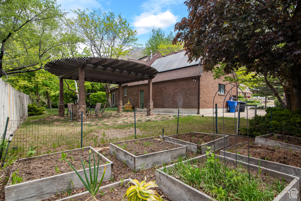 View of yard featuring a garden, a pergola, and fence