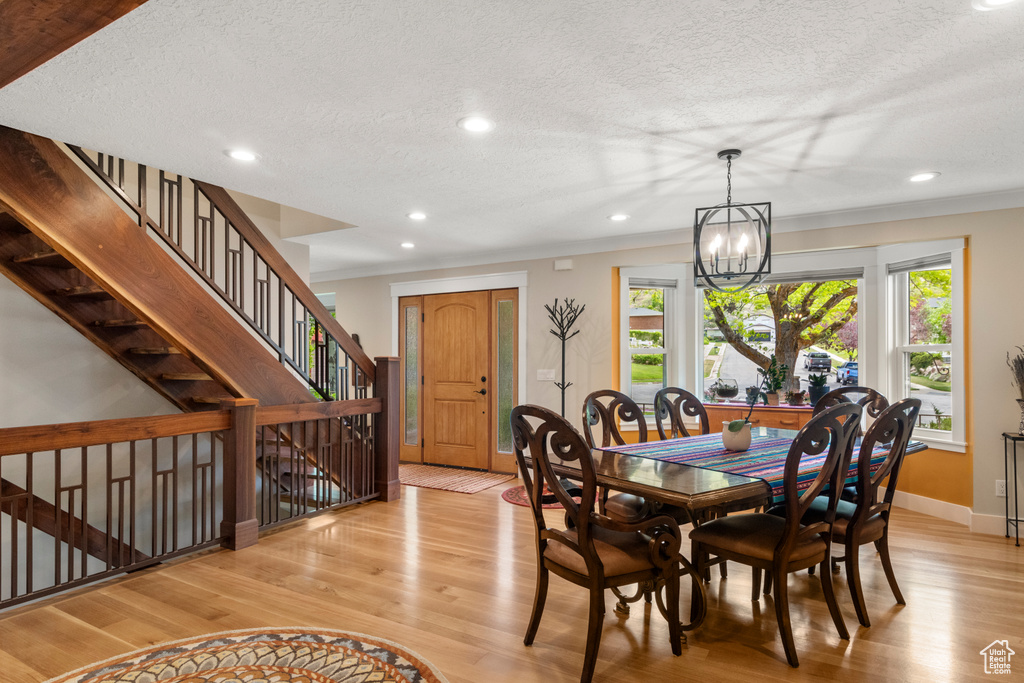 Dining area with a textured ceiling, light wood-type flooring, a chandelier, recessed lighting, and baseboards