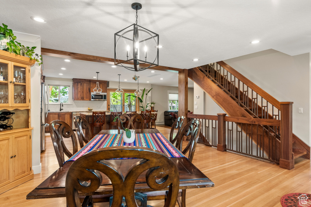 Dining space featuring a chandelier, light wood-style floors, recessed lighting, stairs, and baseboards