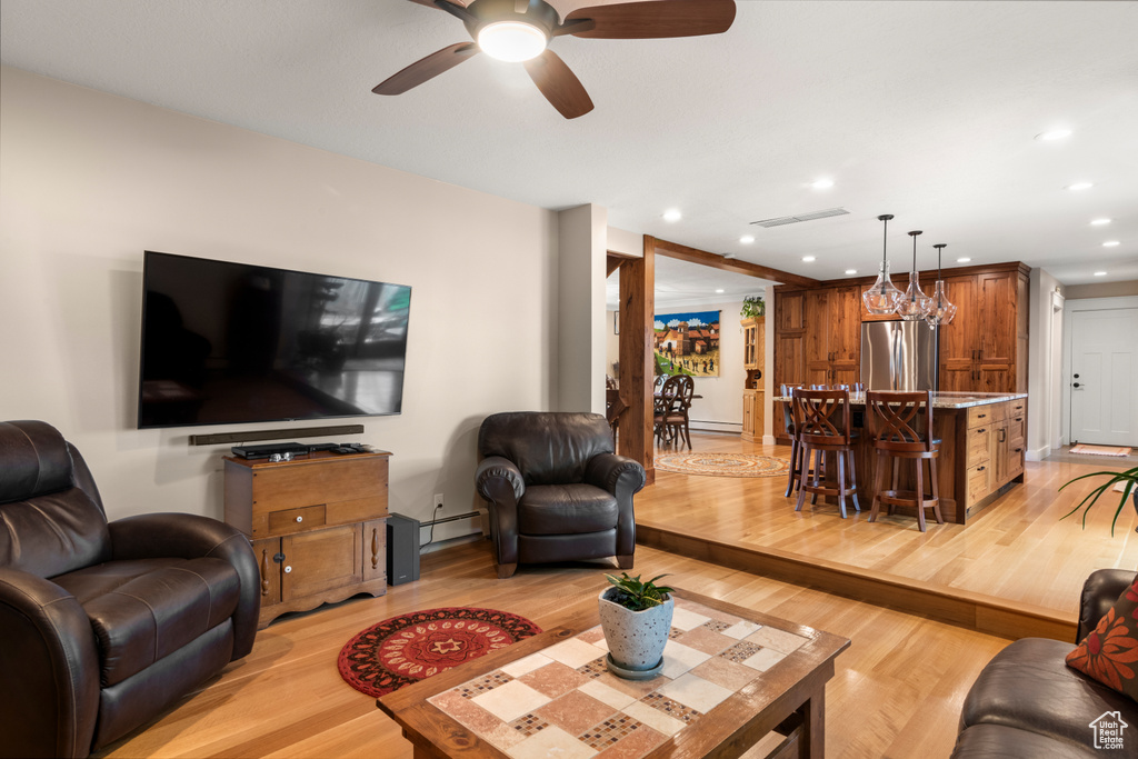 Living room featuring light wood-style floors, a ceiling fan, recessed lighting, baseboard heating, and a baseboard heating unit
