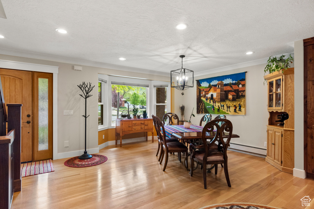 Dining space with a chandelier, light wood finished floors, a textured ceiling, ornamental molding, and recessed lighting