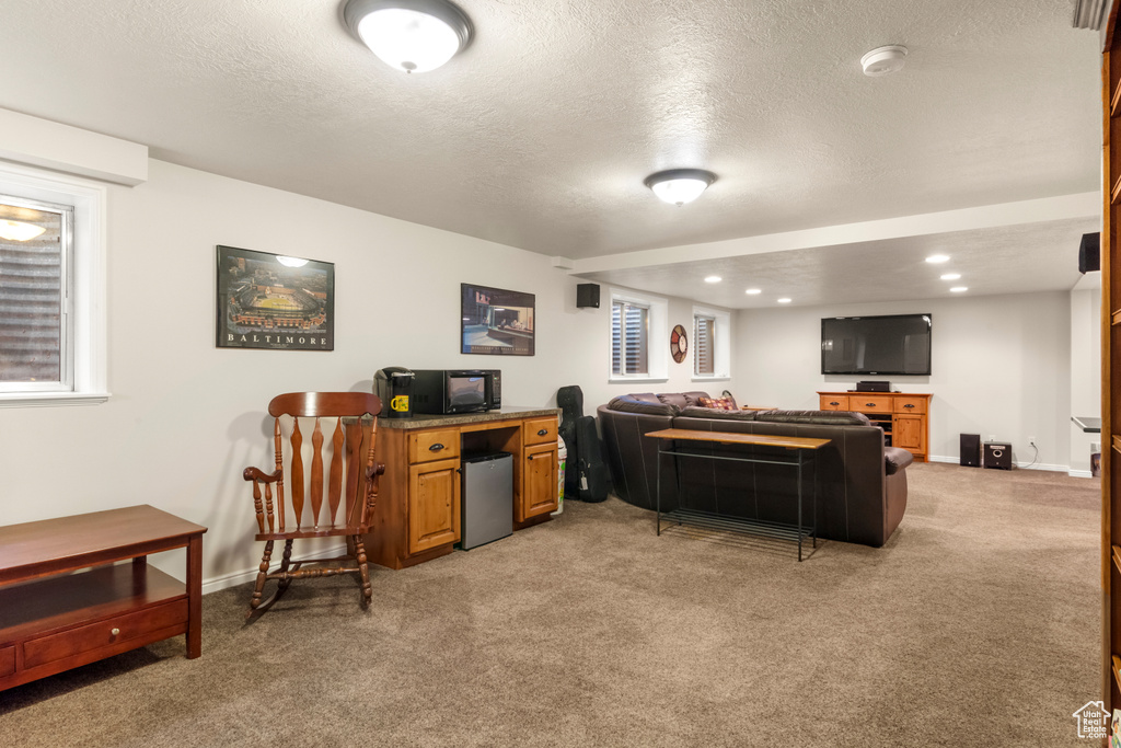 Living room with light carpet, a textured ceiling, baseboards, and recessed lighting