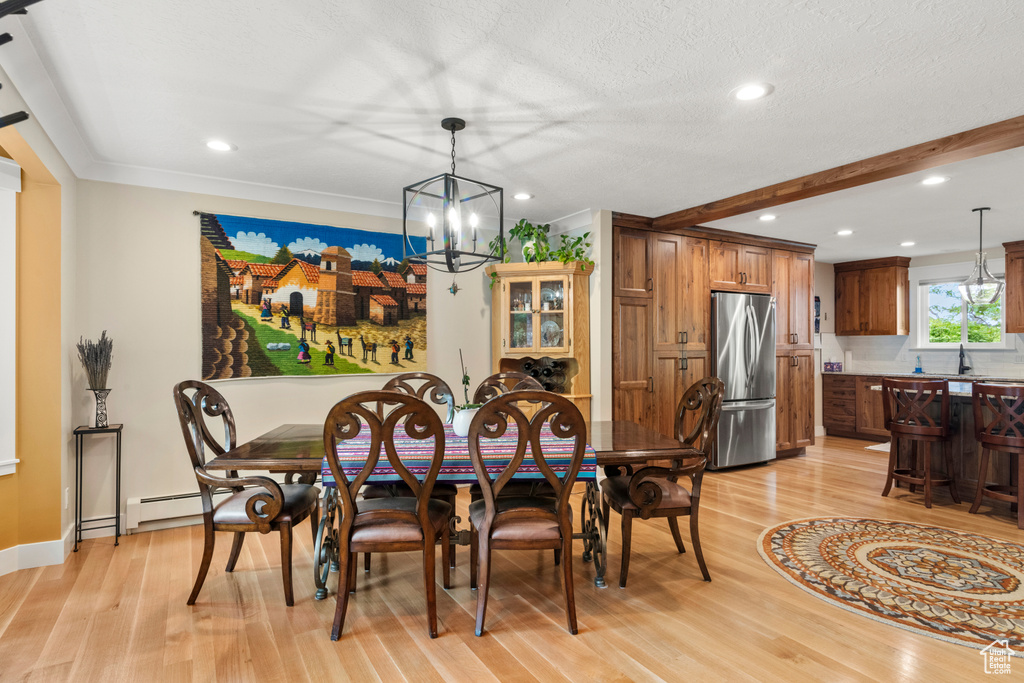 Dining area with light wood-style floors, a chandelier, a baseboard heating unit, recessed lighting, and ornamental molding